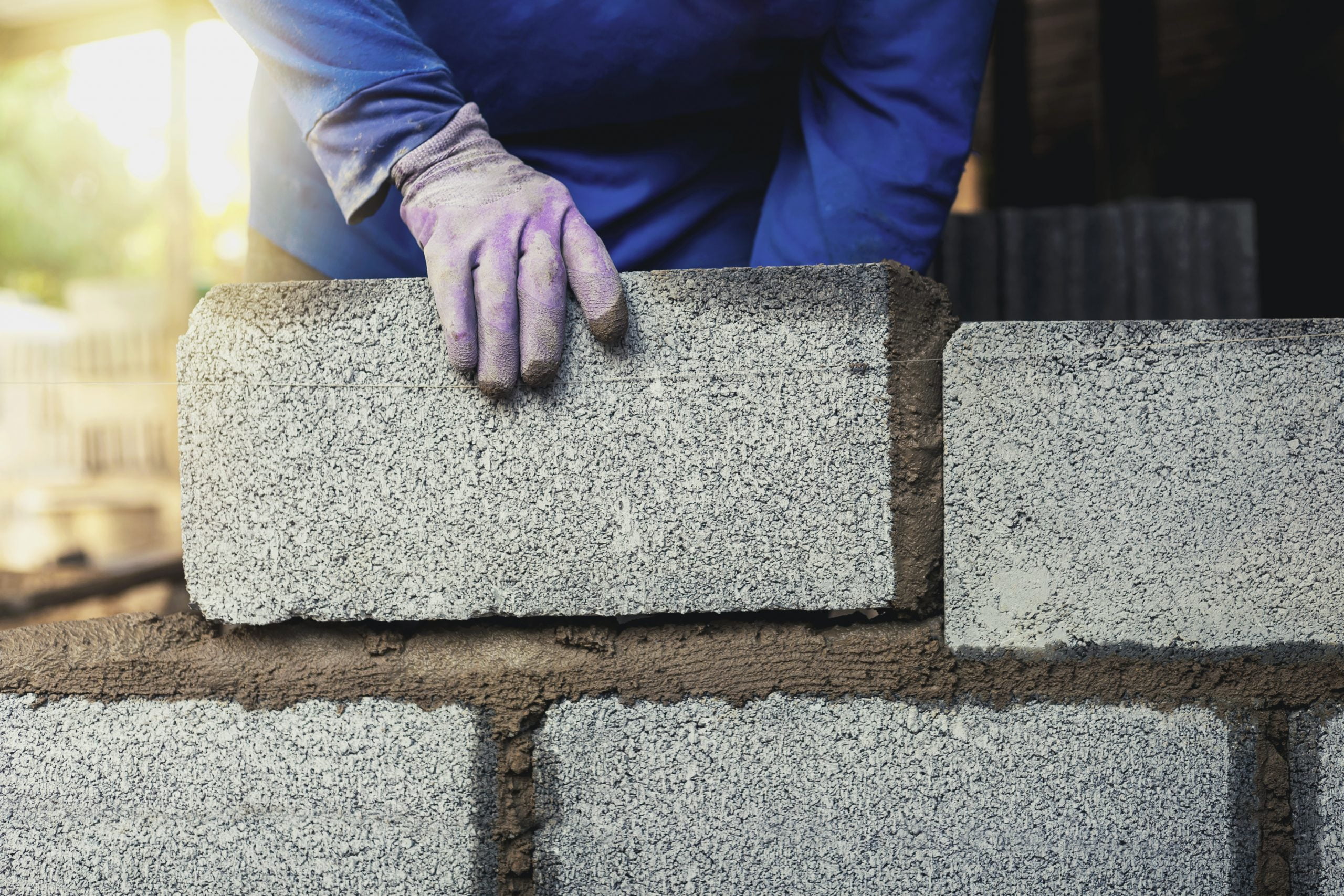 Construction workers are building cement walls with brick blocks